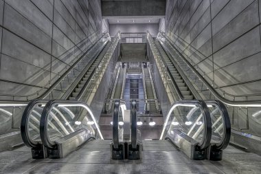 Kopenhag 'daki Amagerbro Metro İstasyonu' nda gri fütürist bir ışıkta yürüyen merdiven.