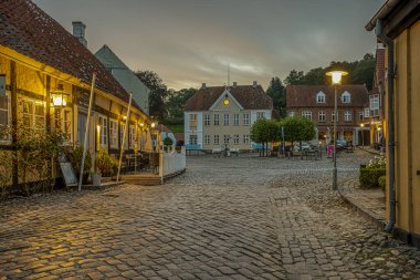 old cobblestone square with a half-timbered hotel in the evening twiligt hour, Mariager, Denmark, August 7, 2022
