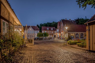 Hotel Postgaarden at a cobblestone square in the soft light from streetlamps during the twilight hour, Mariager, Denmark, August 6, 2022