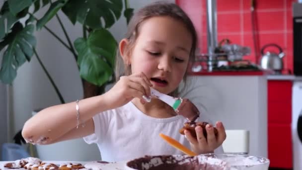 Cheerful kid is dancing while decorates homemade gingerbread with icing — Video