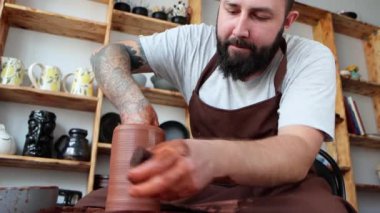Hipster sakallı zanaatkarın portresi çömlekçilik atölyesinde kilden bir vazo yapar, 4K video.