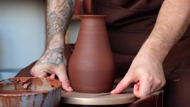 男性の陶芸家は作品を仕上げ 陶芸家のホイールから完成した花瓶を削除し 棚に置きます クローズアップ4Kビデオ — ストック動画