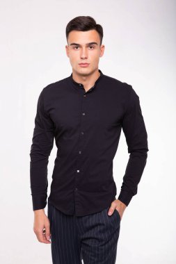 moda portre siyah gömlekli genç adamın kontrast gölgeler ile duvarın üzerinden poz veriyor