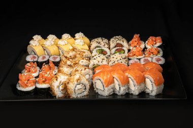 Set of Different Sushi and Rolls over Black Background