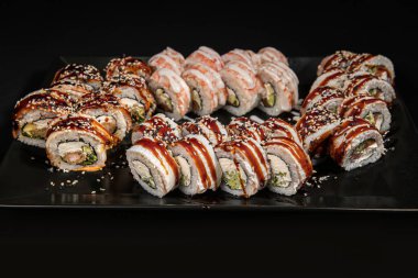 Set of Different Sushi and Rolls over Black Background