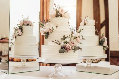 Süs olarak kalın kremalı düğün pastası ve kurumuş güller. Bu görüntü sığ bir alan derinliğine sahip.