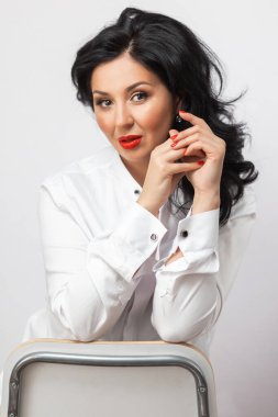 Parlak mavi makyajlı güzel bir genç kadının portresi. Dudaklarında parlak kırmızı ruj olan güzel bir esmer. Uzun siyah saçlı güzel bir kız. Esmer kadının yakın çekim yüzü..