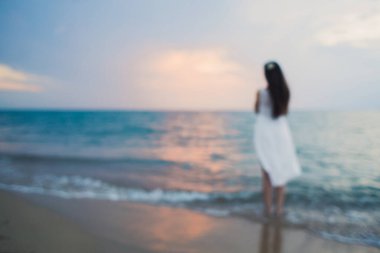 Beyaz elbiseli, sevecen erkek ve kız el ele tutuşurken arka plan bulanıklaşıyor.