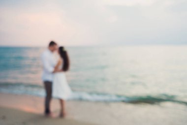 Beyaz elbiseli, sevecen erkek ve kız el ele tutuşurken arka plan bulanıklaşıyor.