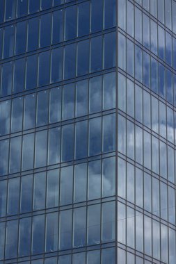 Gökyüzü arka planında cam cepheli modern ofis binası. Ofis binasının şeffaf cam duvarı.