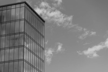 Gökyüzü arka planında cam cepheli modern ofis binası. Ofis binasının şeffaf cam duvarı.