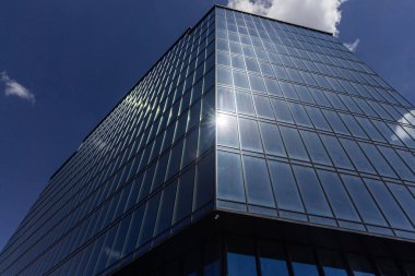 Gökyüzü arka planında cam cepheli modern ofis binası. Ofis binasının şeffaf cam duvarı.