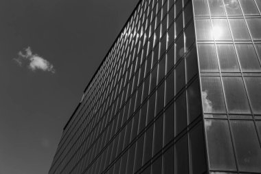 Gökyüzü arka planında cam cepheli modern ofis binası. Ofis binasının şeffaf cam duvarı.