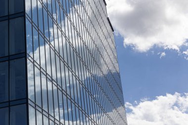 Gökyüzü arka planında cam cepheli modern ofis binası. Ofis binasının şeffaf cam duvarı.