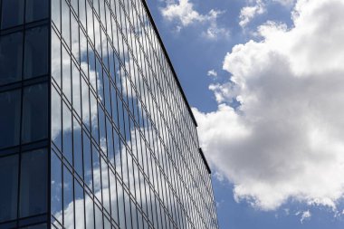 Gökyüzü arka planında cam cepheli modern ofis binası. Ofis binasının şeffaf cam duvarı.