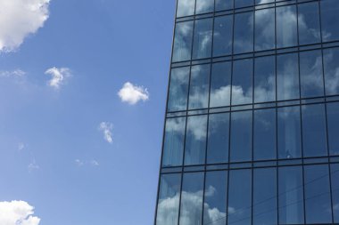 Gökyüzü arka planında cam cepheli modern ofis binası. Ofis binasının şeffaf cam duvarı.