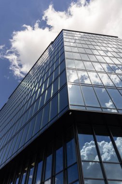 Gökyüzü arka planında cam cepheli modern ofis binası. Ofis binasının şeffaf cam duvarı.