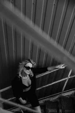 Güneş gözlüklü, siyah deri ceketli kızıl saçlı manken. Peri saç kesimi. Serseri, rock tarzı moda.