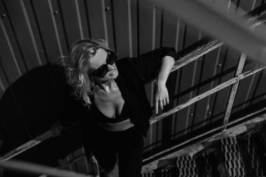 Güneş gözlüklü, siyah deri ceketli kızıl saçlı manken. Peri saç kesimi. Serseri, rock tarzı moda.