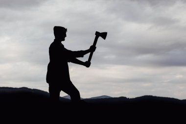 Elinde ağır bir balta olan bir adam. Ağaç gövdelerini kesen ya da kesen bir oduncunun elinde bir balta. Bir adam köydeki bir evin bahçesinde odun kesiyor..