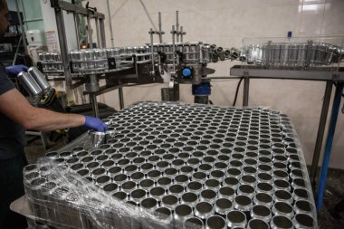 Bira fabrikasında bira şişeleme teknolojisi. Boş alüminyum bira kutuları taşıyıcı bant boyunca hareket ediyor. Temiz bira şişeleri taşıyıcı boyunca ilerliyor. Endüstri, üretim hattı.