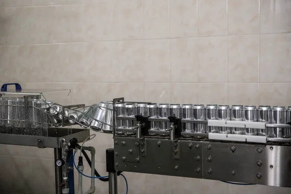 Technological line for bottling of beer in brewery. Empty aluminum beer cans are moving along the conveyor belt. Clean beer bottles are moving along the conveyor.Industry, production line