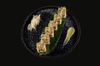 Suşi ve kızarmış sarımsaklı karides, taştan bir tabakta karides ve siyah arka plan.