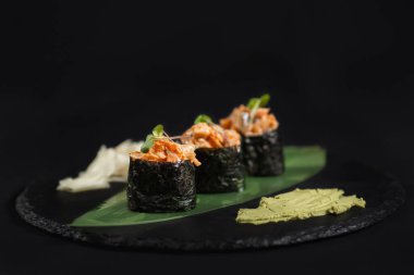 Suşi ve kızarmış sarımsaklı karides, taştan bir tabakta karides ve siyah arka plan.