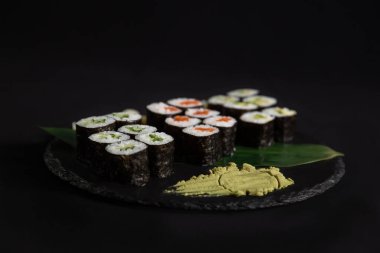 Suşi ve kızarmış sarımsaklı karides, taştan bir tabakta karides ve siyah arka plan.