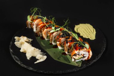 Suşi ve kızarmış sarımsaklı karides, taştan bir tabakta karides ve siyah arka plan.