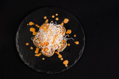 Suşi ve kızarmış sarımsaklı karides, taştan bir tabakta karides ve siyah arka plan.