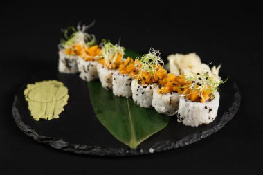 Suşi ve kızarmış sarımsaklı karides, taştan bir tabakta karides ve siyah arka plan.