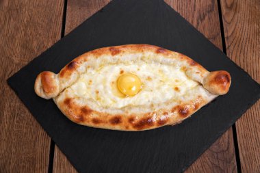 Kafkas Gürcistan mutfağı: Koyu arkaplanda Adjarian khachapuri.