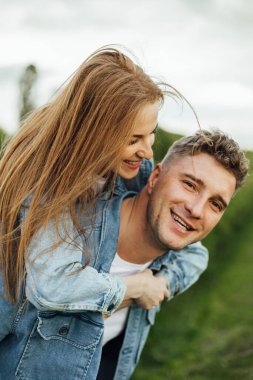 Tam büyümüş bir aile, sıcak bir bahar gününde parkta el ele yürürken, kot ve günlük giysiler içinde genç bir aileyi çekiyor.