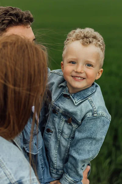 Full growth shot young family in denim casual clothes walking around the park holding hands on warm spring day