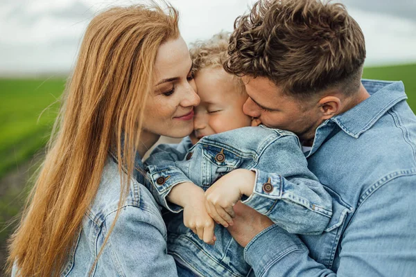 Full growth shot young family in denim casual clothes walking around the park holding hands on warm spring day