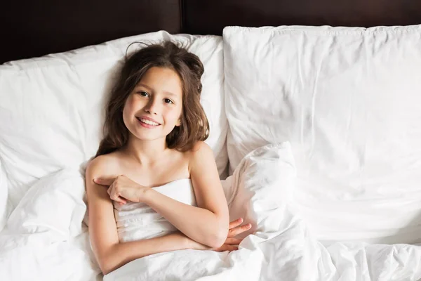 Happy family lying under blanket in bed at home