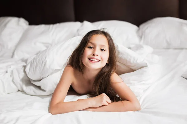 Happy family lying under blanket in bed at home