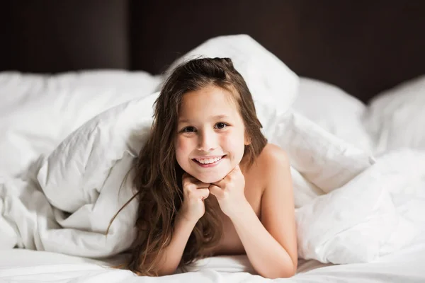 Happy family lying under blanket in bed at home