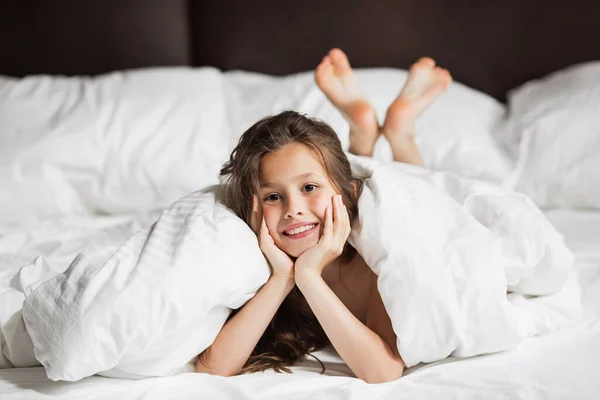 Happy family lying under blanket in bed at home