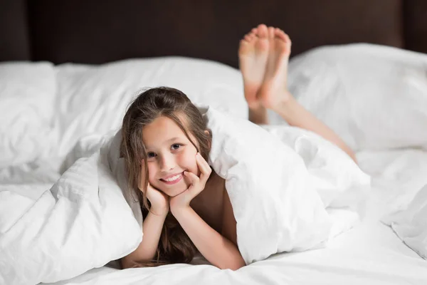 Happy family lying under blanket in bed at home