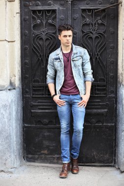 Stylish guy standing street in a denim jacket against, men's looks