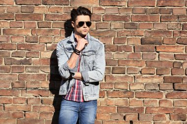 Stylish guy standing street in a denim jacket against, men's looks
