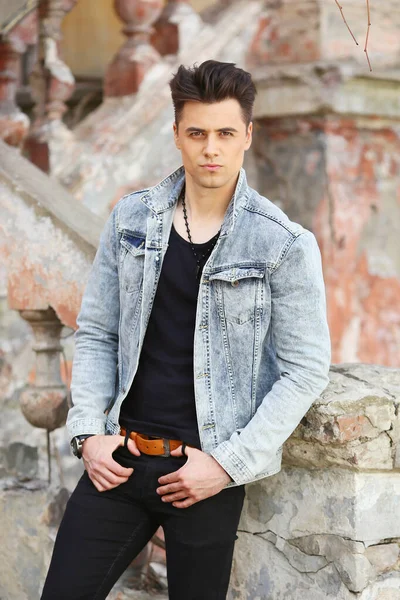 Stylish guy standing street in a denim jacket against, men's looks