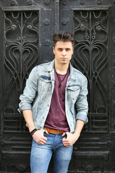 Stylish guy standing street in a denim jacket against, men's looks