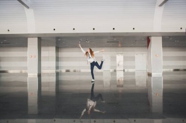 Şık, güzel bir kız, elinde biletlerle havaalanı terminalinde kameraya bakan mutlu bir kız. Moda kadın portresi. Havaalanı terminali. İş gezisi