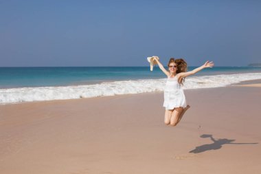 Kameraya bakarak tropik sahilde beyaz bikinili genç kadın portresi. Mayo kopya alanı ile güzel latin kız. Yaz tatil ve bronzlaşma kavramı.