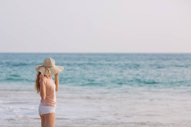 Kameraya bakarak tropik sahilde beyaz bikinili genç kadın portresi. Mayo kopya alanı ile güzel latin kız. Yaz tatil ve bronzlaşma kavramı.