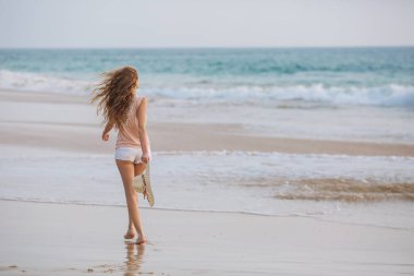 Kameraya bakarak tropik sahilde beyaz bikinili genç kadın portresi. Mayo kopya alanı ile güzel latin kız. Yaz tatil ve bronzlaşma kavramı.