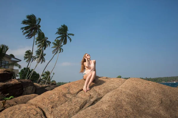 Portrait of young woman in white bikini on tropical beach looking at camera. Beautiful latin girl in swimwear with copy space. Summer vacation and tanning concept.